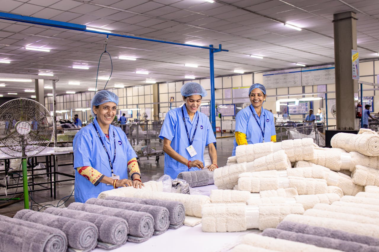 Group of textile workers arranging towels in a brightly lit factory.